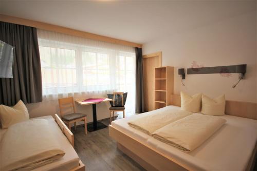 sypialnia z dwoma łóżkami, biurkiem i oknem w obiekcie Kinderhotel Stefan w mieście Wenns