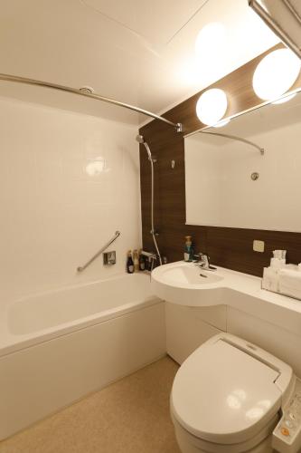 een badkamer met een toilet, een wastafel en een bad bij Green Hill Hotel Onomichi in Onomichi