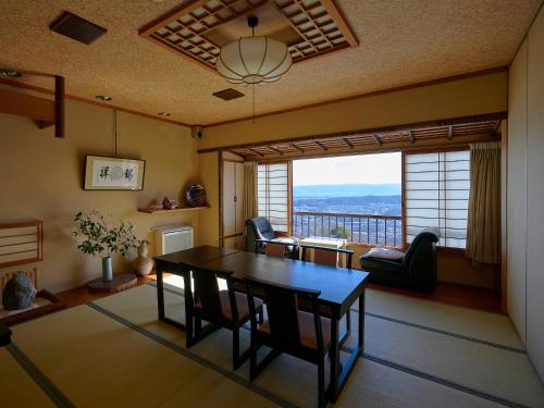 a dining room with a table and a large window at Shiroyama Ryokan in Ikuma