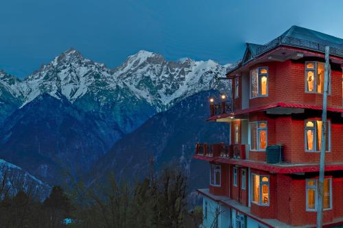 a building with lights on in front of a mountain at Echor - The Alpine Crest in Kalpa
