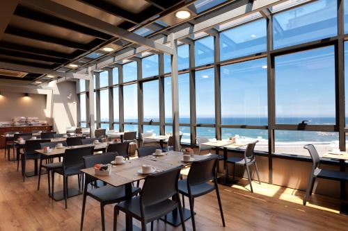 a restaurant with tables and chairs and large windows at Hotel Príncipe de Asturias in Gijón