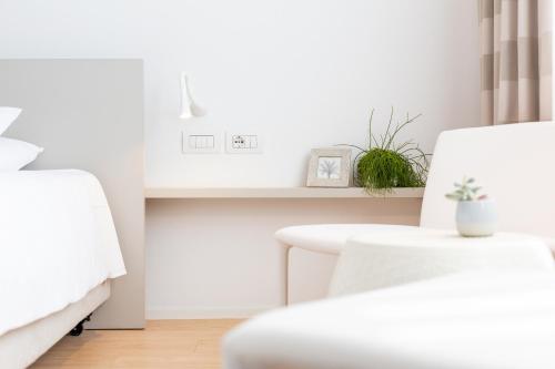 a white room with two beds and a table at Hotel Lago Di Garda in Nago-Torbole