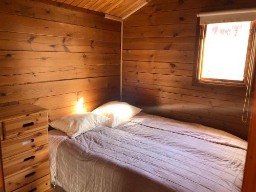 a bedroom with a bed in a wooden cabin at Three Rooms stuga i stugby near National Park in Undenäs