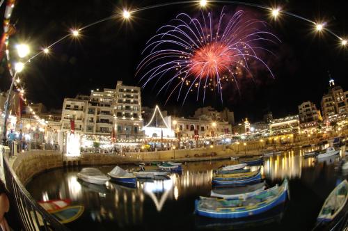 a fireworks display over a harbor with boats in the water at St Julians Bay Sea Front Apartments in St Julian's