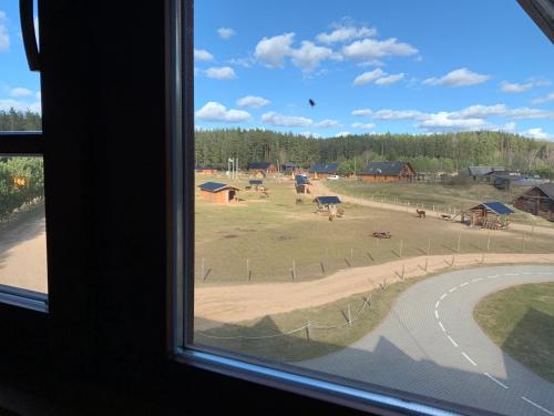 a window with a view of a field with houses at Rakši in Cēsis