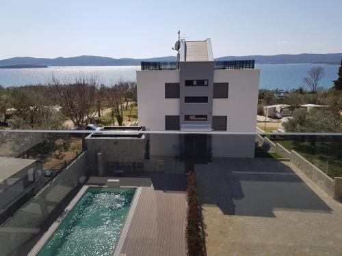a house with a swimming pool next to the water at Villa Ivan in Sveti Filip i Jakov