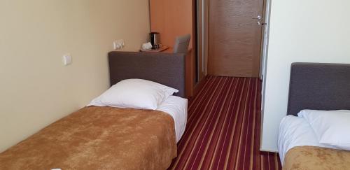 a hotel room with two beds and a door at Hotel Dainava in Druskininkai