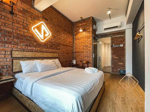 Un dormitorio con una pared de ladrillo y una cama grande en Brick Box Ipoh by Verve, en Ipoh