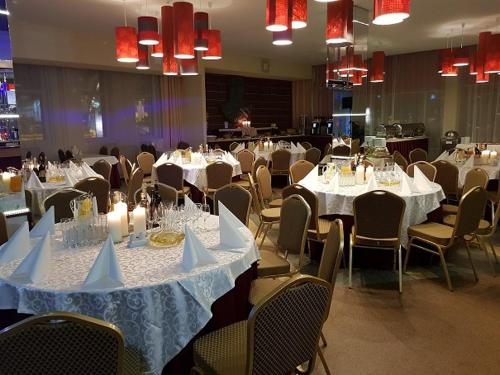 a dining room with white tables and chairs at Hotel Dainava in Druskininkai