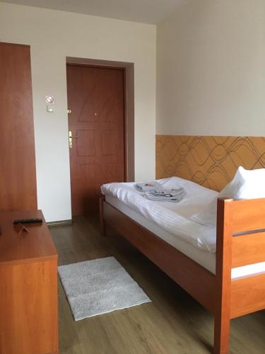 a small bedroom with a bed and a wooden door at Noclegi Wałbrzych - Pokoje Konrad in Wałbrzych