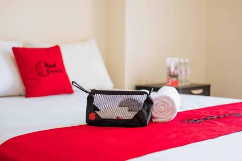a bed with a red blanket and a bag on it at RedDoorz near Cipinang Indah Mall in Jakarta