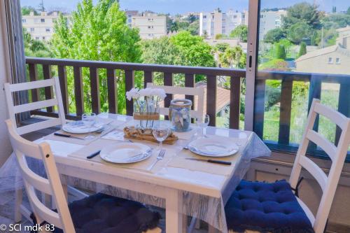 une table avec des assiettes et des verres sur un balcon dans l'établissement Sanary sur mer,Soleil et douceur II, à Sanary-sur-Mer