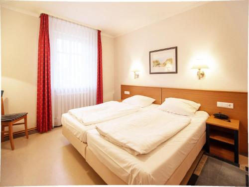 Un dormitorio con una gran cama blanca y una ventana. en Dünenpark Binz - Klassik Ferienwohnung mit 1 Schlafzimmer und Balkon im Obergeschoss 018, en Binz