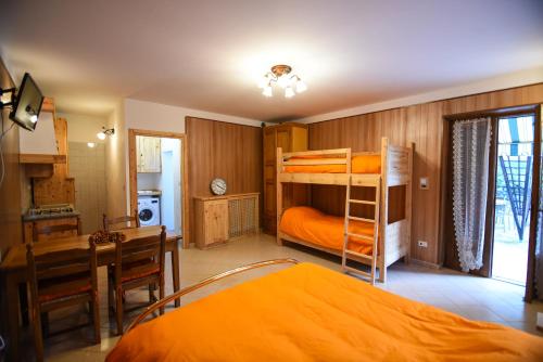 a bedroom with bunk beds and a table and a kitchen at IL NIDO DEL FALCO in Pradleves