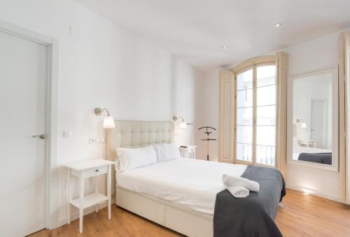 una camera bianca con un letto e una finestra di Urbe10 Plaza de la Constitucion 1 Bedroom Apartment a Málaga