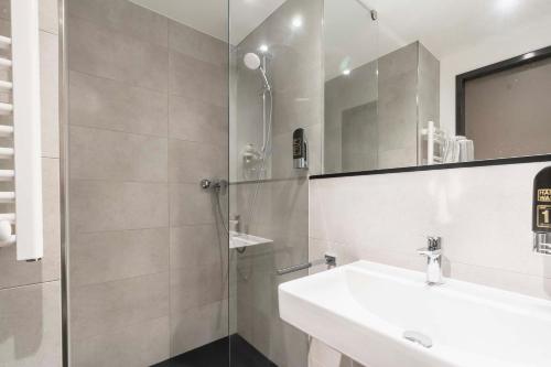 a bathroom with a sink and a shower with a mirror at Abasto Hotel München Feldmoching in Munich