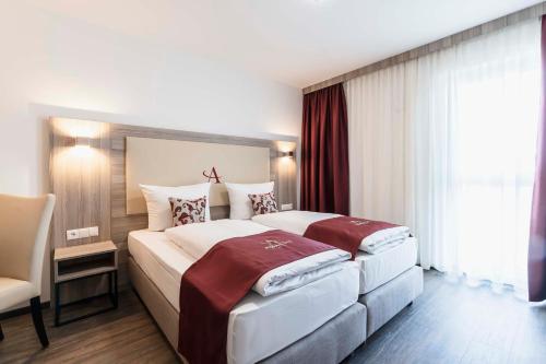 ein Hotelzimmer mit 2 Betten und einem Stuhl in der Unterkunft Abasto Hotel München Feldmoching in München