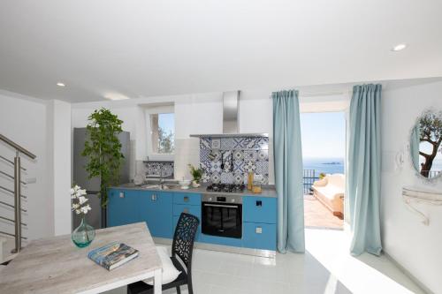 a kitchen with blue cabinets and a table with a view of the ocean at YourHome - Casa Ivi Positano in Positano