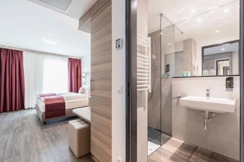 a bathroom with a sink and a bed at Abasto Hotel München Feldmoching in Munich