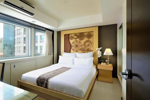 a bedroom with a large white bed and a window at Quest Hotel & Conference Center Cebu in Cebu City
