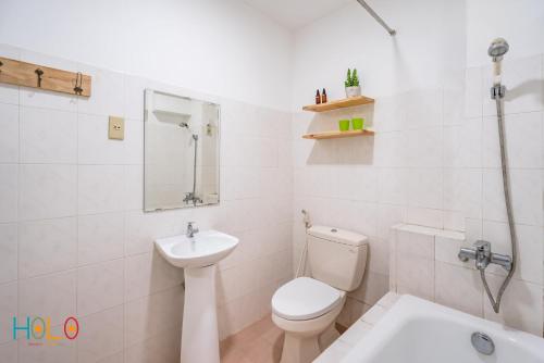 a white bathroom with a toilet and a sink at HoLo Fairy House Saigon - Serviced Homestay in Ho Chi Minh City