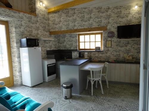 a kitchen with a refrigerator and a table and chairs at LA FORGE DU LUCIMOND in Saint-André