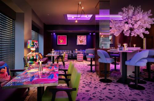 a restaurant with tables and chairs and purple lighting at NYX Hotel London Holborn by Leonardo Hotels in London