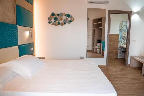 a bedroom with a large white bed and a hallway at AQUA SARDINIA boutique hotel in Budoni