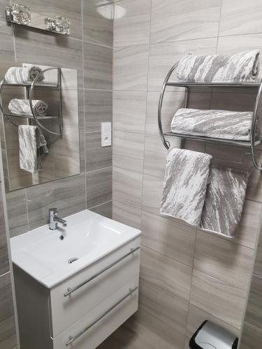 a bathroom with a sink and a mirror and towels at Flamingó Apartmanház in Hévíz