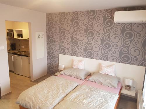 um quarto com uma cama e uma parede com um padrão em Flamingó Apartmanház em Hévíz