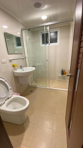 La salle de bains est pourvue de toilettes, d'un lavabo et d'une douche. dans l'établissement Murakami Travel Guest House, à Huxi