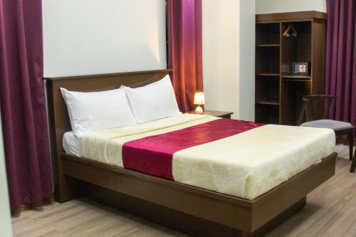 a bedroom with a large bed with purple curtains at A.M @ 93rd HOTEL in Olongapo