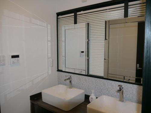 La salle de bains est pourvue de 2 lavabos et d'un miroir. dans l'établissement 江津良別邸, à Shirahama