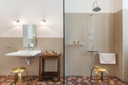 a bathroom with a sink and two gold stools at Hotel Le Grimaldi by Happyculture in Nice