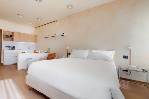 a bedroom with a large white bed and a kitchen at 1881 LUXURY SUITES in Verona