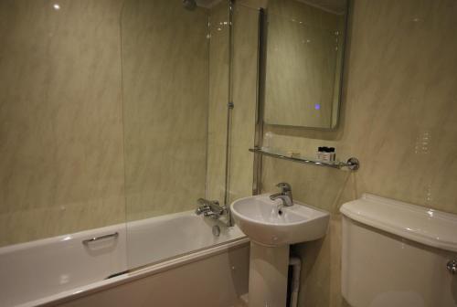 a bathroom with a sink and a tub and a toilet at The Kellbank in Gosforth