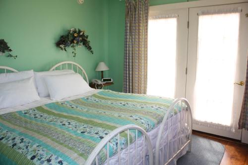 a white bed in a room with green walls at The White House Inn in Cooperstown