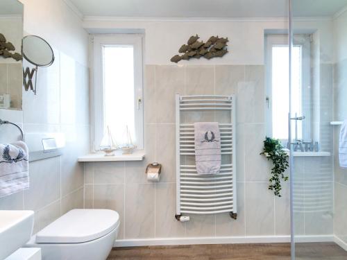a bathroom with a toilet and a glass shower at Dünenrose in Tinnum
