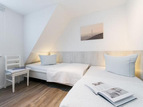 two beds in a small room with a newspaper on the bed at Dünenrose in Tinnum