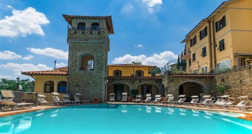 a swimming pool in front of a building with a clock tower at Villa La Malva in Poggio alla Malva