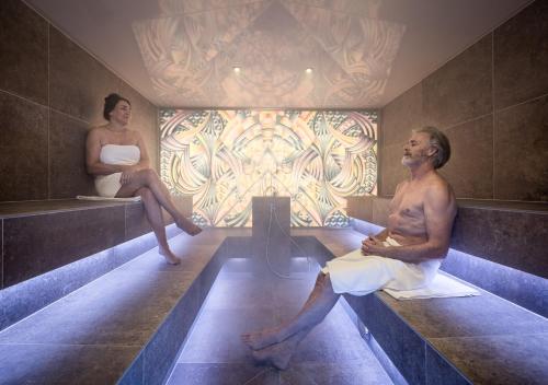 ナウダースにあるAlpin Art & Spa Hotel Naudererhof Superiorの浴槽に腰掛けた男女