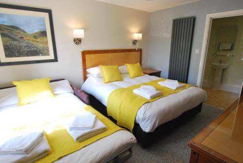 a hotel room with two beds with yellow sheets at The Kellbank in Gosforth