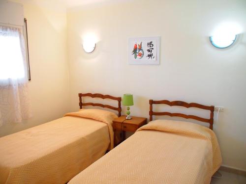 una habitación con dos camas y una mesa con lámpara en MIRAMAR 23A, en Roses