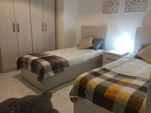 a bedroom with two beds and a dresser with a night stand at Bugibba Sunrise View Modern Apartment in St Paul's Bay