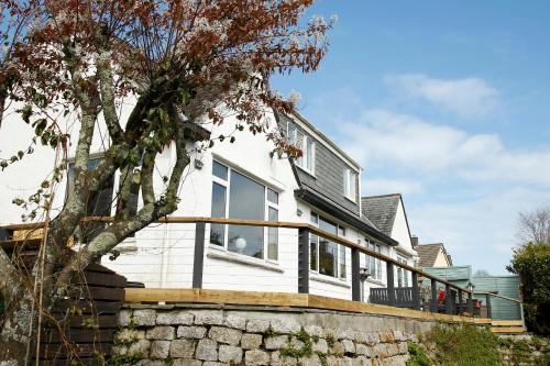 a white house with a deck on a stone wall at The Dog House, Penryn in Penryn