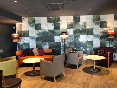 a lobby with a couch and tables and chairs at ibis Styles Clermont-Ferrand Aéroport in Clermont-Ferrand