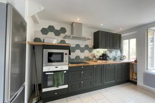 - une cuisine avec des placards gris et un four micro-ondes dans l'établissement La mystérieuse maison du Robimouth, à Saint-Satur