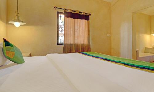 a large white bed in a room with a window at Treebo Morjim Banyan Resort in Morjim