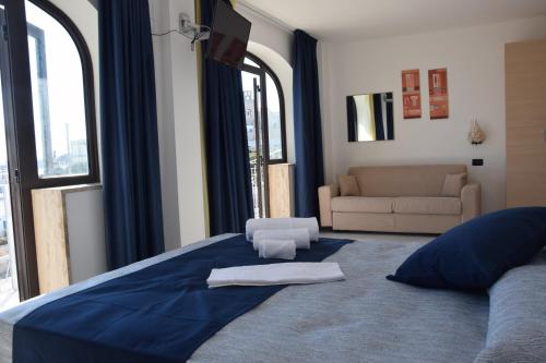 a bedroom with a large blue bed with a couch at Hotel Profumo Di Mare in Otranto