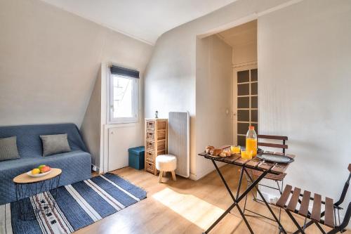 un salon avec un canapé bleu et une table dans l'établissement New Parisian Studio with View in the Central 11th, à Paris